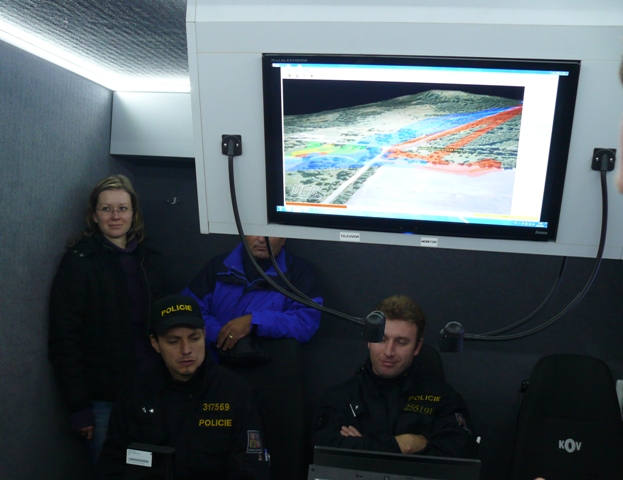 H) Štábní vozidlo s 3D projekcí a polohou pátracích týmů